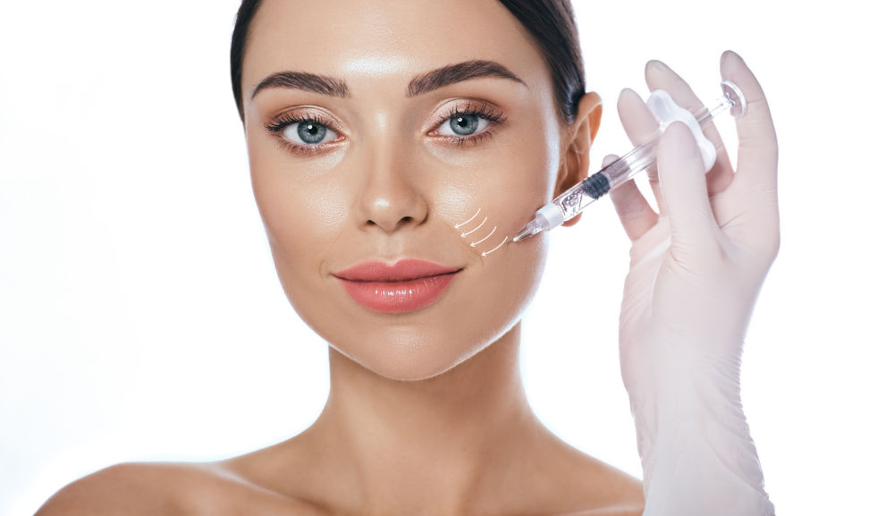 Beautician doing injection into the nasolabial folds. Correction of wrinkles on the female face using dermal fillers